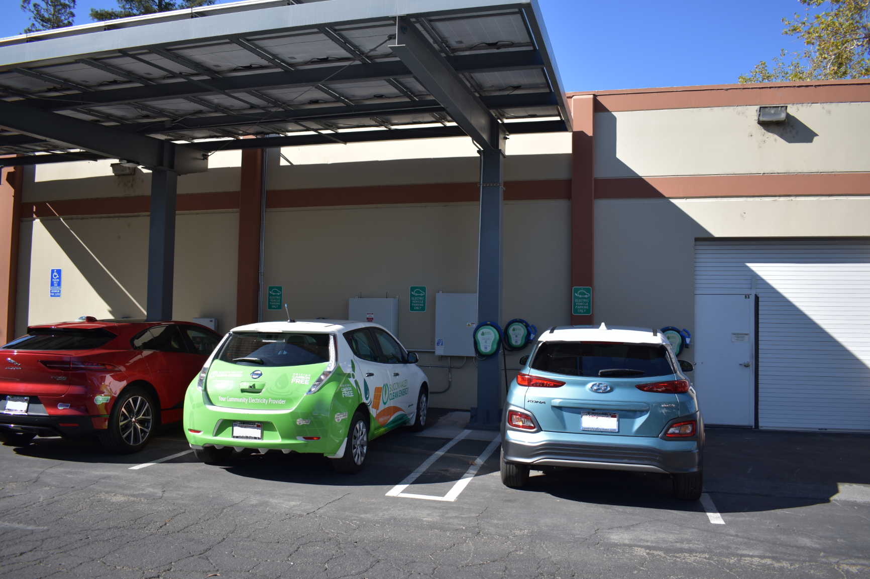 image of three cars charging under solar panel canopy