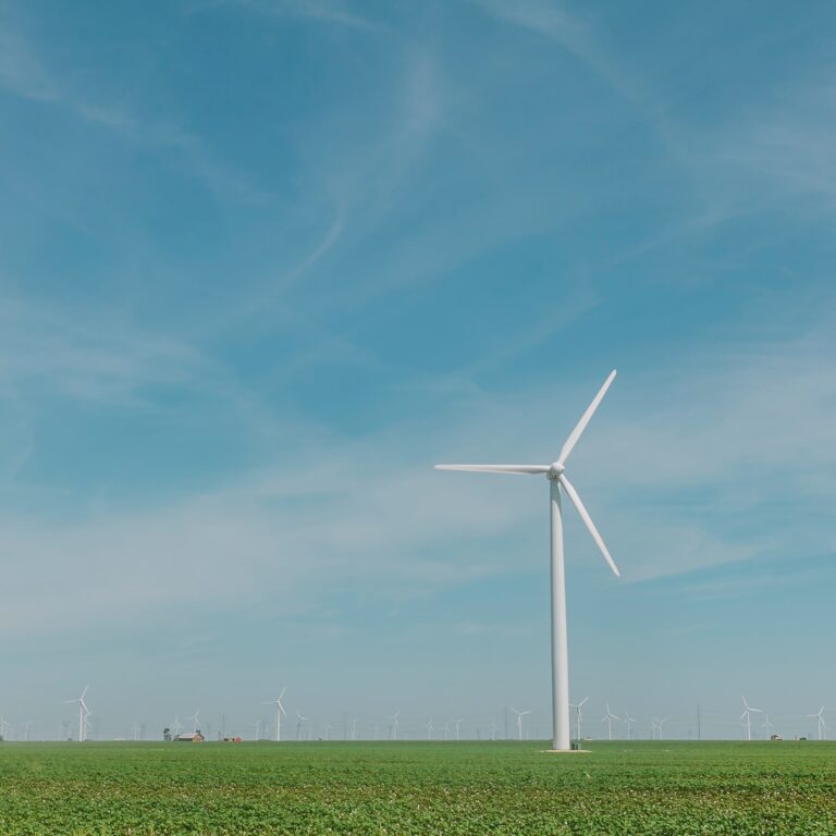 wind turbine on a green farm land against blue skies and dusted with wispy clouds