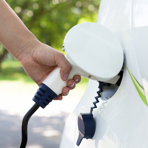 hand plugging in a charger to electric vehicle