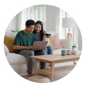 Couple sitting on a couch with dog looking at laptop